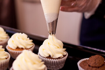 Filling cupcakes with soft cream close-up.