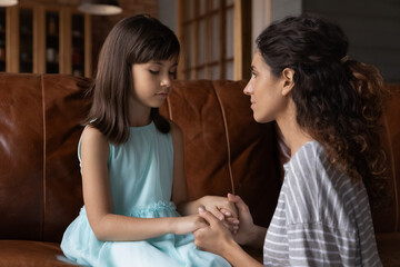 Close up caring young mother comforting calming upset offended little daughter, holding hands,...