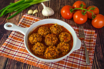Meatballs with tomato sauce in a frying pan on a wooden table. Selective focus. 