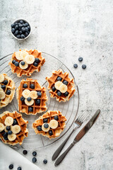 Fototapeta na wymiar Top view of fresh made waffles with blueberries, banana and yoghurt