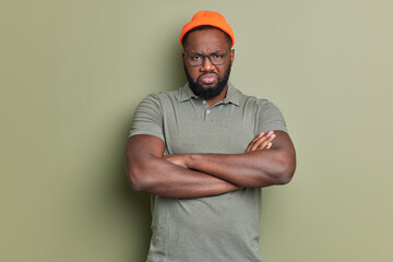 Photo of offended bearded man keeps arms folded looks with dissatsfied expression being insulted by...
