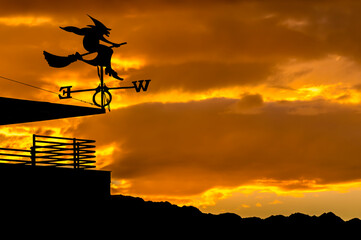 Silhouette of weather vane with witch flying on broomstick. Weather vane is instrument showing...
