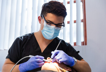 Men dentist wearing protective face mask examining a patient