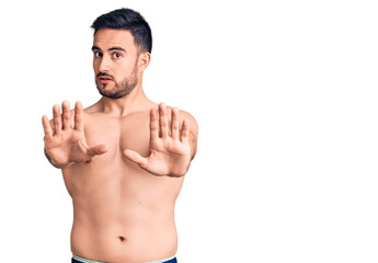 Fototapeta premium Young handsome man wearing swimwear doing stop gesture with hands palms, angry and frustration expression