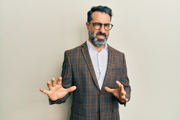Middle age man with beard and grey hair wearing business jacket and glasses disgusted expression,...