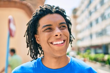 Young african american man smiling happy looking to the side at street of city.