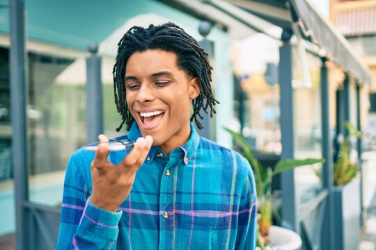 Young african american man sending audio message using smartphone at street of city.
