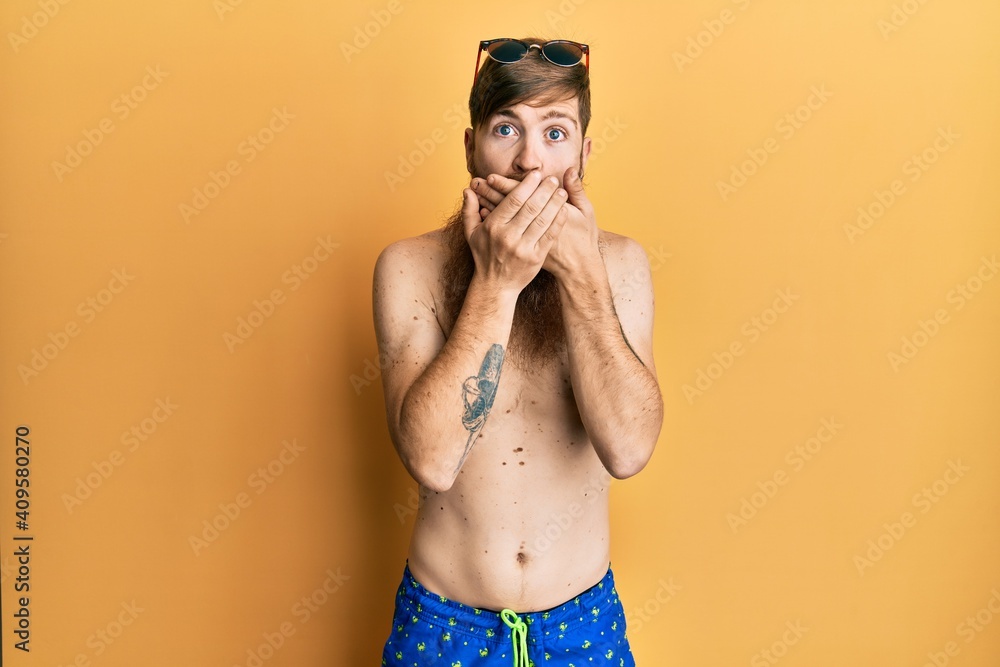 Poster Redhead man with long beard wearing swimsuit and sunglasses shocked covering mouth with hands for mistake. secret concept.