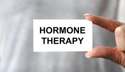 A girl holds a business card with hormone THERAPY tacts.