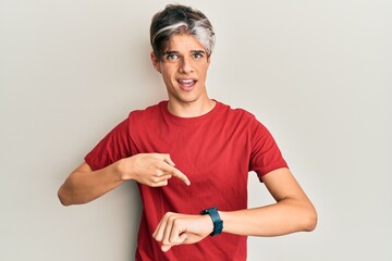 Young hispanic man wearing casual clothes in hurry pointing to watch time, impatience, upset and...