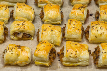 Fresh and flaky puff pastry pasty filled with cabbage and champignon mushroom placed on parchment paper