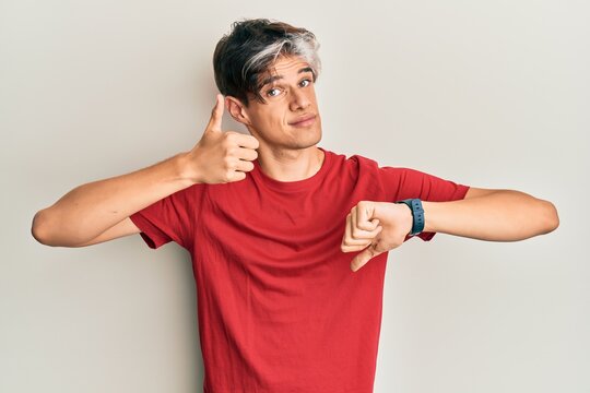 Young hispanic man wearing casual clothes doing thumbs up and down, disagreement and agreement expression. crazy conflict