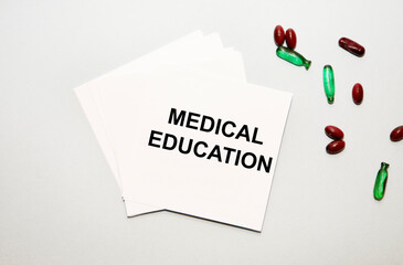 On the sheets for notes the text of Medical Education, next to red and green capsules.