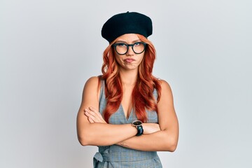 Young redhead woman wearing fashion french look with beret skeptic and nervous, disapproving expression on face with crossed arms. negative person.