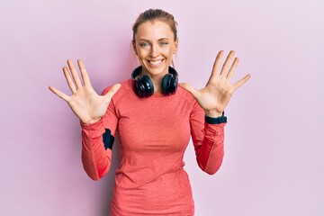 Beautiful caucasian woman wearing sportswear and arm band showing and pointing up with fingers...