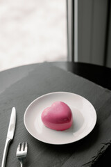 Delightful, luxury, romantic mousse cake in the form heart served on a white plate.. Valentine's Day on February 14. Dark Background.