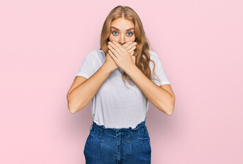 Young caucasian girl wearing casual white t shirt shocked covering mouth with hands for mistake. secret concept.