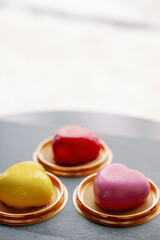 Composition of three mousse cakes in the shape of a heart. Desserts and gifts for Valentine's Day and February 14th. Pink, yellow and red glaze colors. Black background