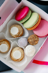 Composition with colorful macaroons, sweets truffle and custard dessert shu in paper box teapot and up of tea on dark background. Gift sets of sweets for Valentine's Day, February 14 and March 8.