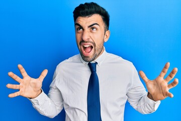 Young hispanic man wearing business clothes crazy and mad shouting and yelling with aggressive expression and arms raised. frustration concept.