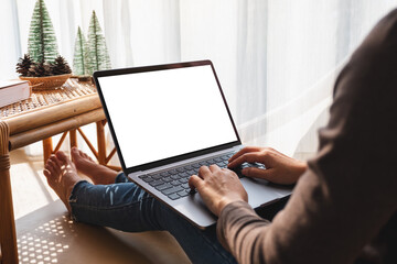 Mockup image of a woman working and typing on laptop computer with blank white screen at home