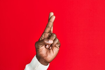 Arm and hand of african american black young man over red isolated background gesturing fingers...