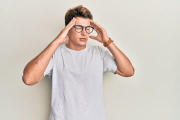 Handsome caucasian man wearing casual clothes and glasses with hand on head, headache because stress. suffering migraine.