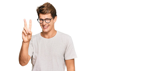 Handsome caucasian man wearing casual clothes and glasses showing and pointing up with fingers number two while smiling confident and happy.