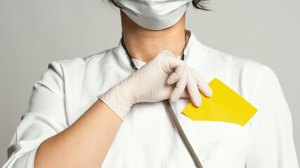 Cropped view of doctor in a white coat and sterile gloves holding yellow blank card