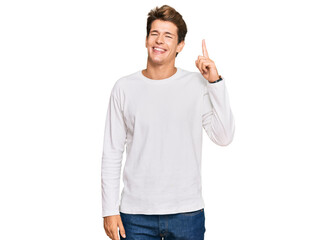 Handsome caucasian man wearing casual white sweater showing and pointing up with finger number one...