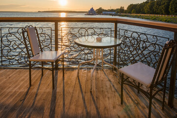 Table and chairs in a cafe on the river embankment on a summer evening at sunset