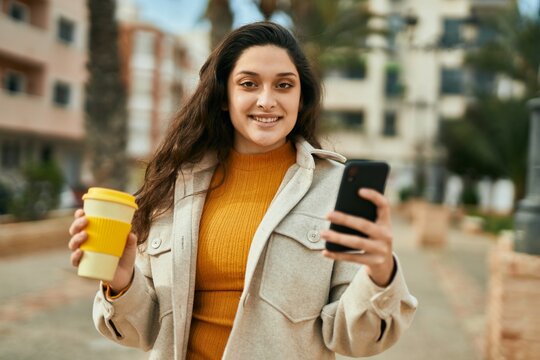 Young middle east woman using smartphone drinking coffee at the city.