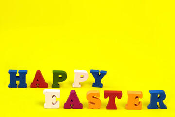 Word Happy Easter of colorful toy alphabet letters isolated on yellow background.