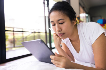 woman using digital tablet in a bed at home. The use of concept of new generation, family, parenthood, authenticity, connection, technology.