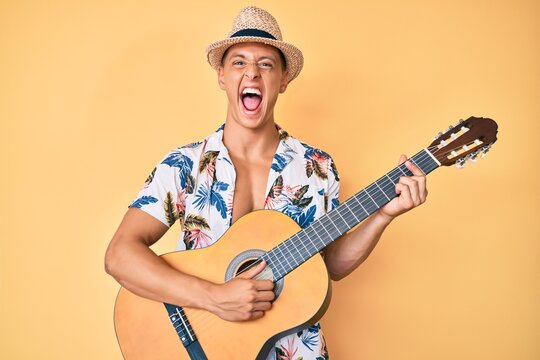Young hispanic boy wearing summer style playing classical guitar celebrating crazy and amazed for success with open eyes screaming excited.