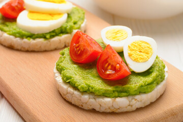 Close up rice cakes with avocado mash and eggs with tomato concept healthy breakfast