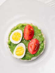 Close up rice cakes with avocado mash and eggs with tomato vertical shot