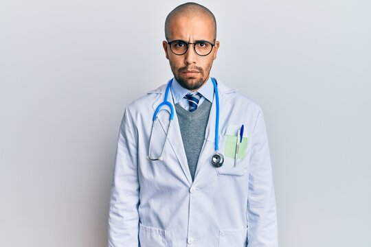 Hispanic adult man wearing doctor uniform and stethoscope skeptic and nervous, frowning upset because of problem. negative person.