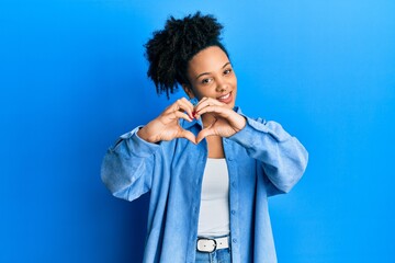 Young african american girl wearing casual clothes smiling in love doing heart symbol shape with hands. romantic concept.