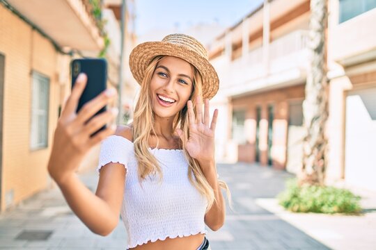 Young blonde tourist girl smiling happy doing video call using smartphone at the city.