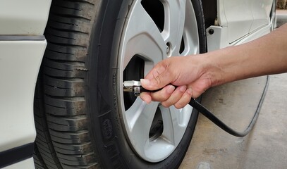 Men's hand are filling the tire.