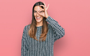 Naklejka premium Young beautiful woman wearing casual clothes doing ok gesture with hand smiling, eye looking through fingers with happy face.