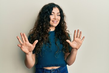 Young brunette woman with curly hair wearing casual clothes showing and pointing up with fingers...