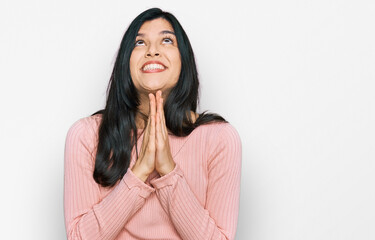 Young hispanic woman wearing casual clothes begging and praying with hands together with hope...
