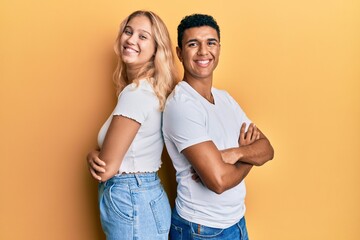 Young interracial couple wearing casual white tshirt happy face smiling with crossed arms looking at the camera. positive person.