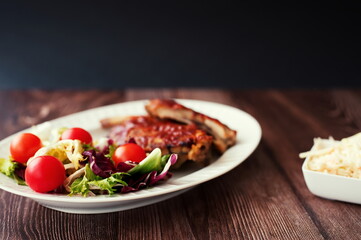 Barbecue ribs with salad and cherry tomato on wooden table