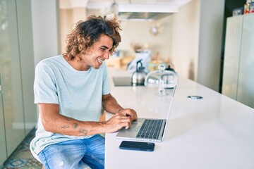 Young hispanic man smiling happy working using laptop at home