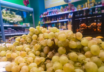 green grapes are sold on a grocery store shelf in the fruit and vegetable section