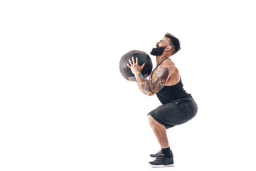 Fototapeta na wymiar Muscular tattooed bearded male exercising fitness weights Medicine Ball in studio isolated on white background.