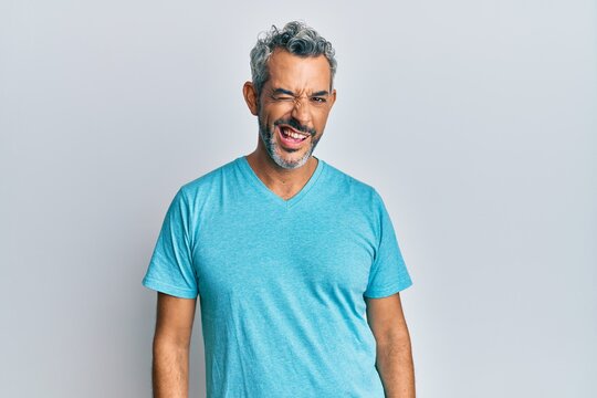 Middle age grey-haired man wearing casual clothes winking looking at the camera with sexy expression, cheerful and happy face.